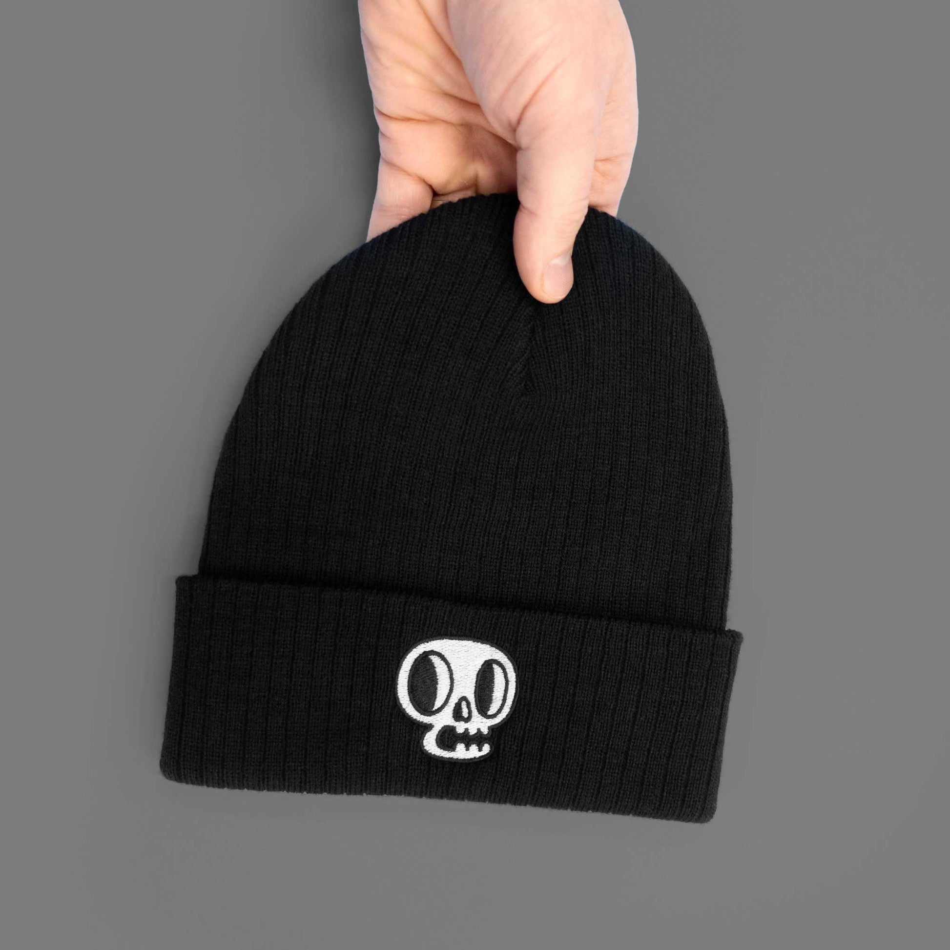 embroidered skull art on plain black ribbed beanie in hand