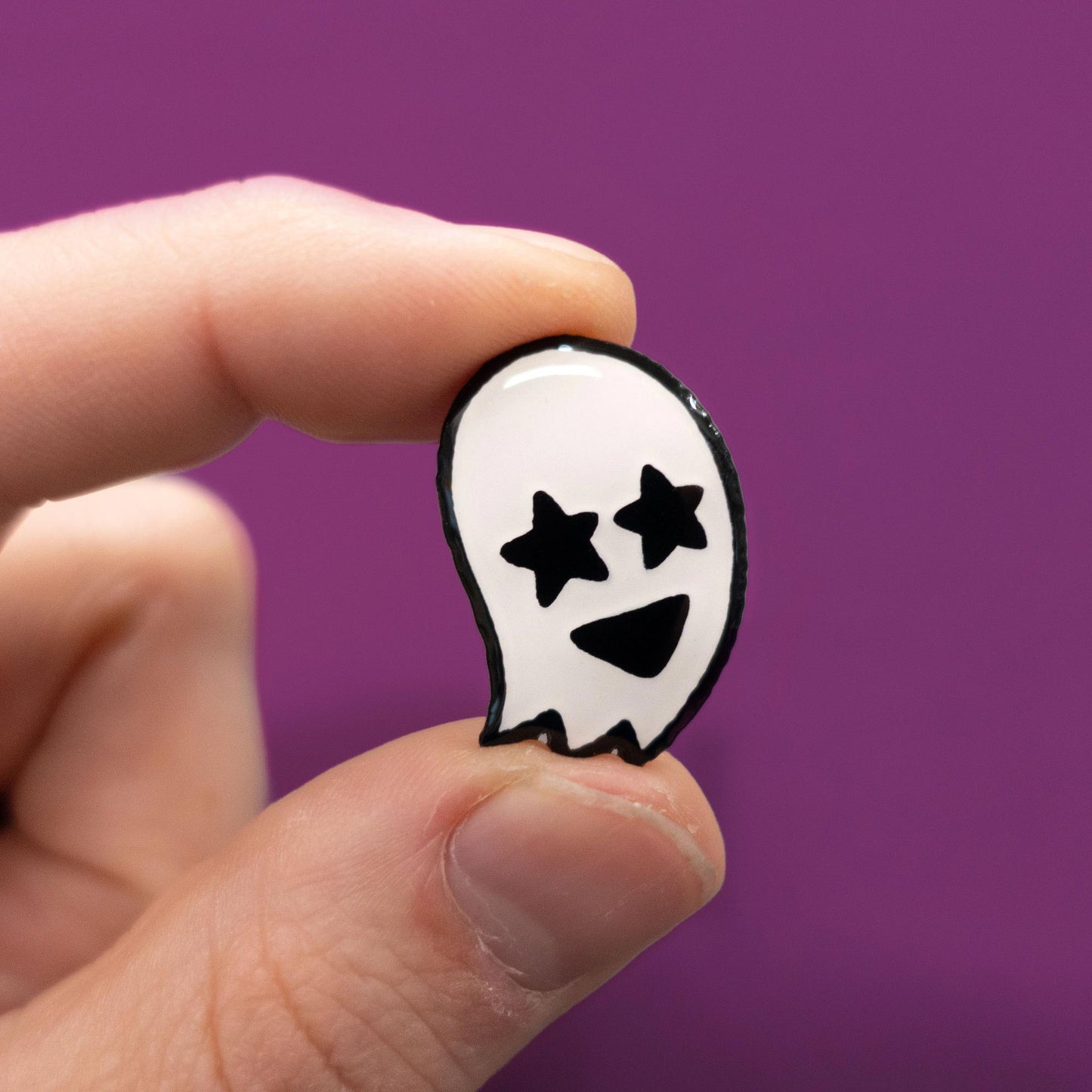 glow in the dark starry eyed ghost enamel pin in hand